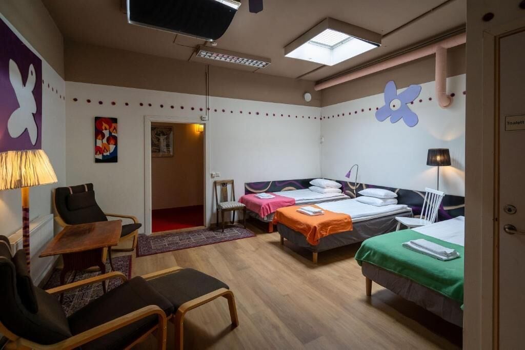 Ein Hotelzimmer mit zwei Betten, einem Schreibtisch, einem Sessel und einem Fernseher.