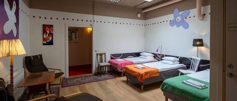 Ein Hotelzimmer mit zwei Betten, einem Schreibtisch, einem Sessel und einem Fernseher.