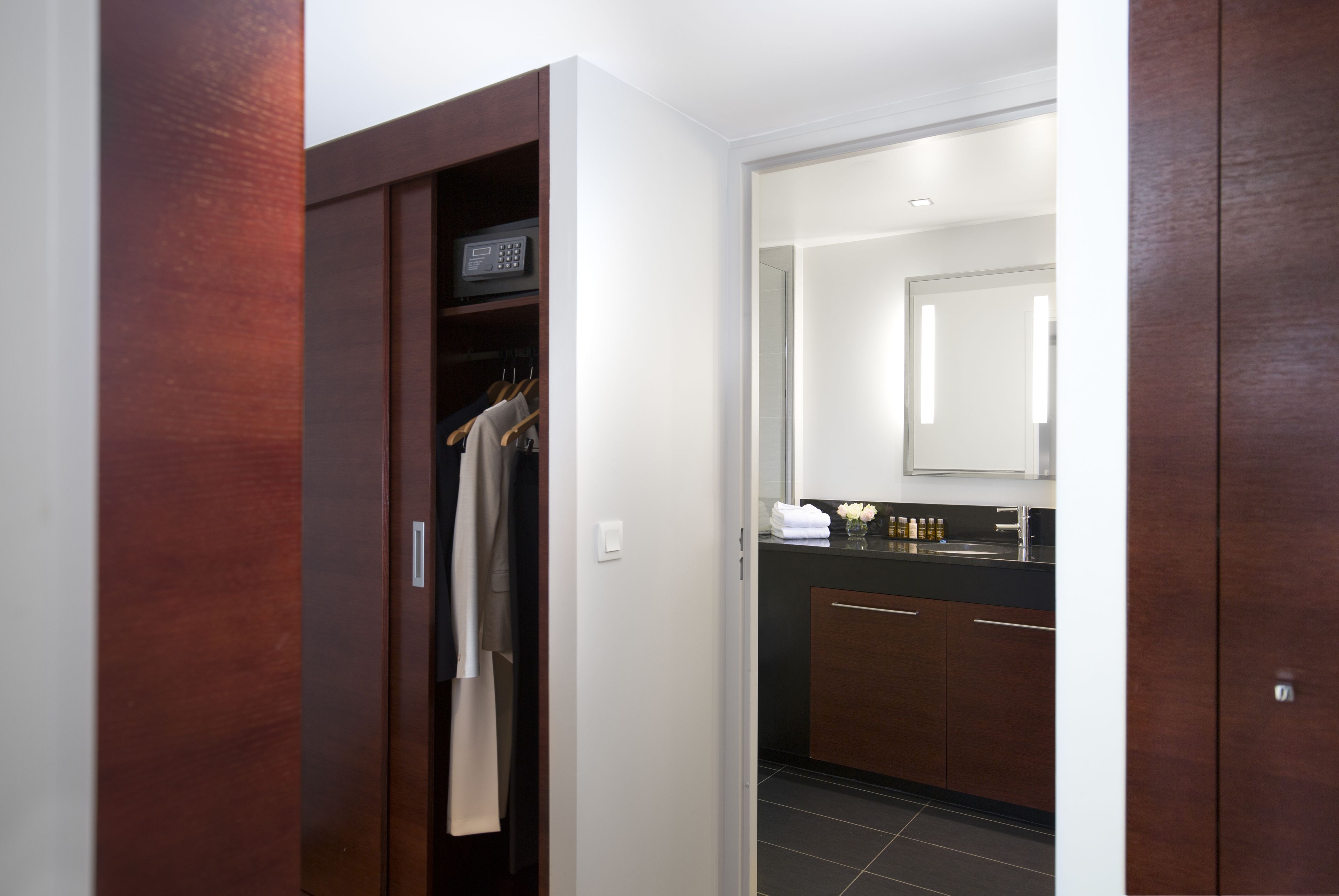A modern bathroom with a dark wood vanity, a mirror, and a towel rack.