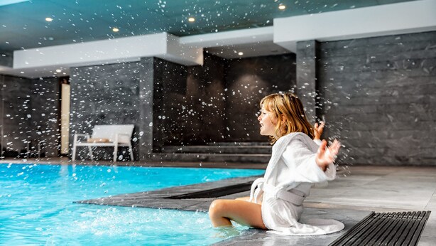 A person sitting by a pool with water jets spraying. - Relais Spa Val d'Europe (Chessy)