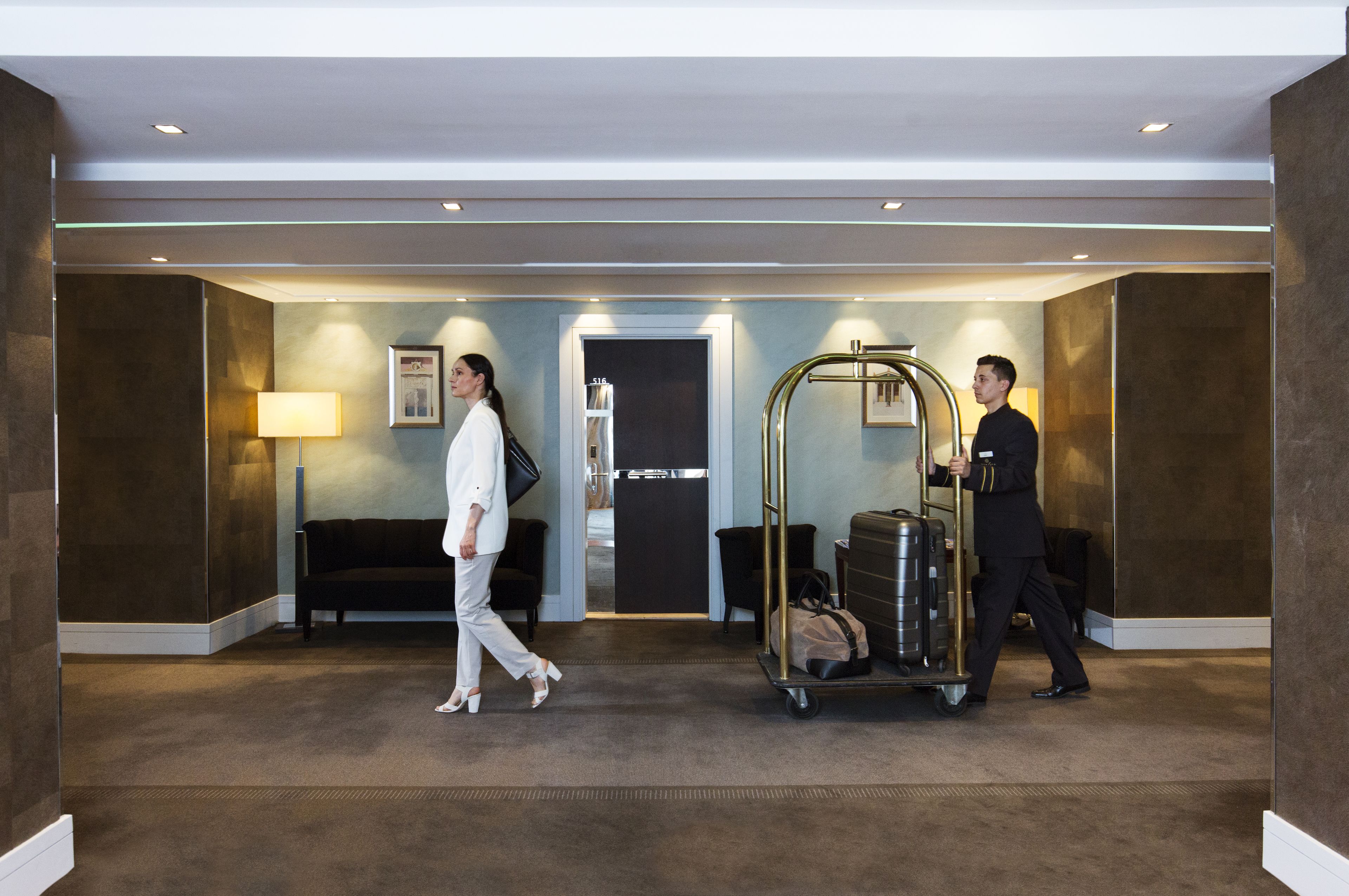 A hotel lobby with a reception desk, a sofa, and a luggage cart.