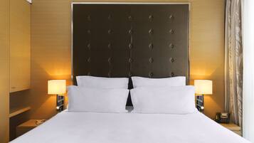 A hotel room with a large bed, two bedside lamps, a wooden headboard, and a nightstand with a telephone.