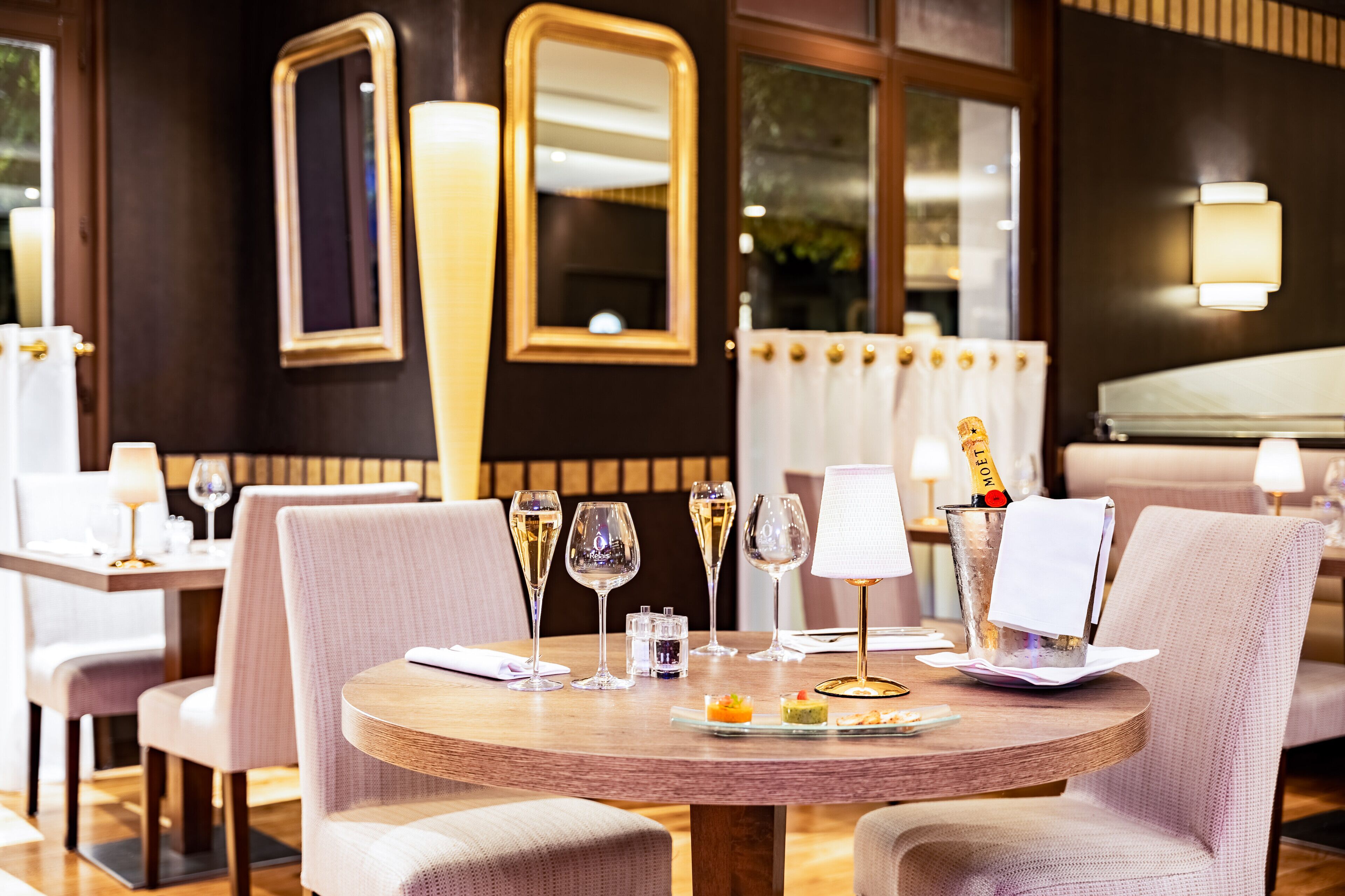 Un espace repas avec des tables rondes, des chaises et des verres à vin.