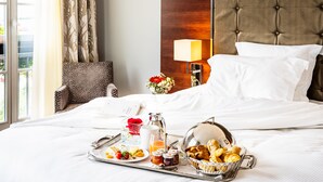 A neatly made bed with white linens, a tray with breakfast items, a vase with flowers, and a lamp on a bedside table. - Relais Spa Val d'Europe (Chessy)