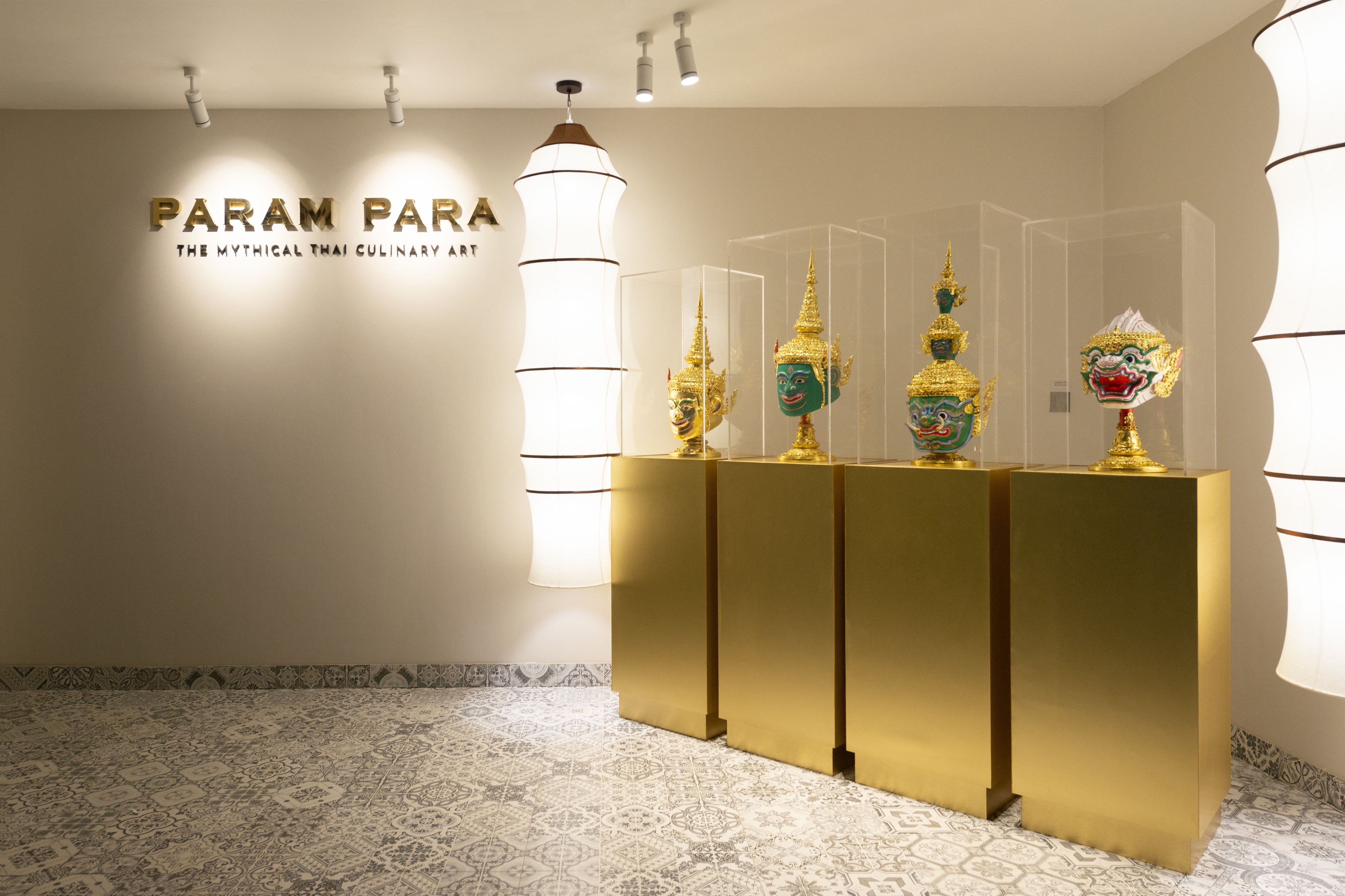 Un espace d’accueil avec un comptoir de réception doré, une enseigne fixée au mur portant l’inscription « PARAM PARA », et des masques traditionnels thaïlandais exposés dans des vitrines.