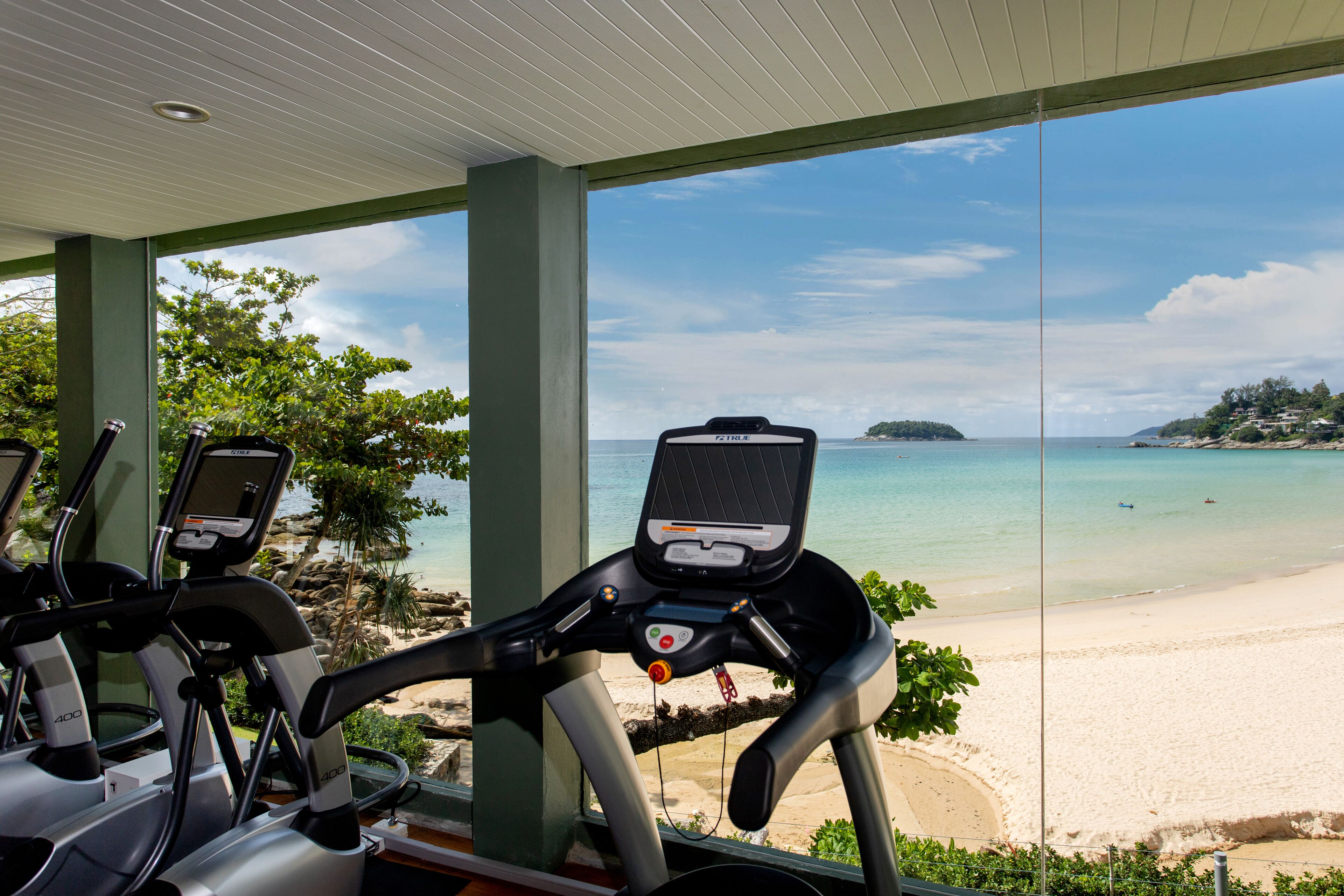 Un espacio techado con bicicletas de ejercicio con vista a la playa.