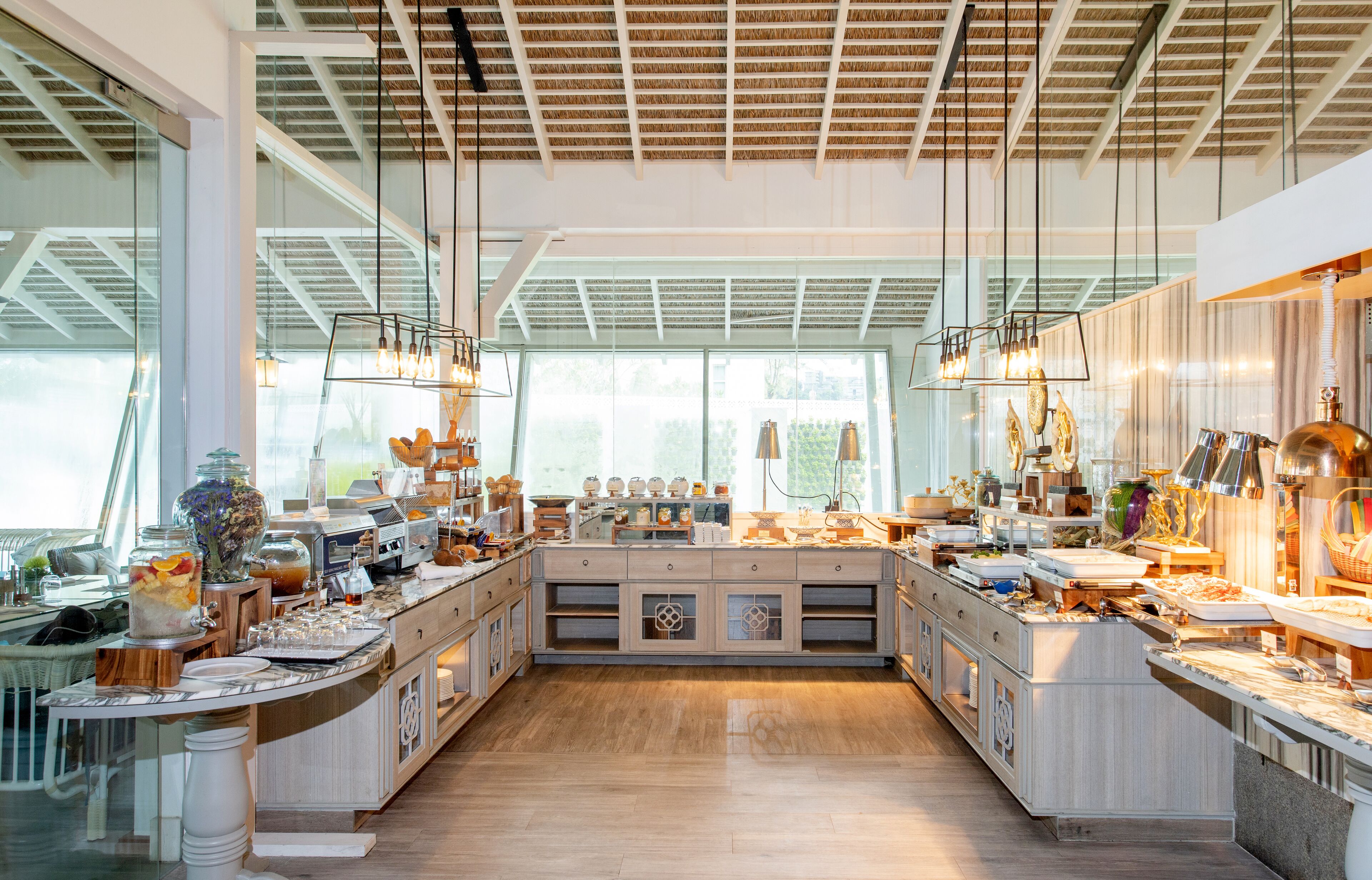 A spacious kitchen with high ceilings, large windows, and modern lighting fixtures.