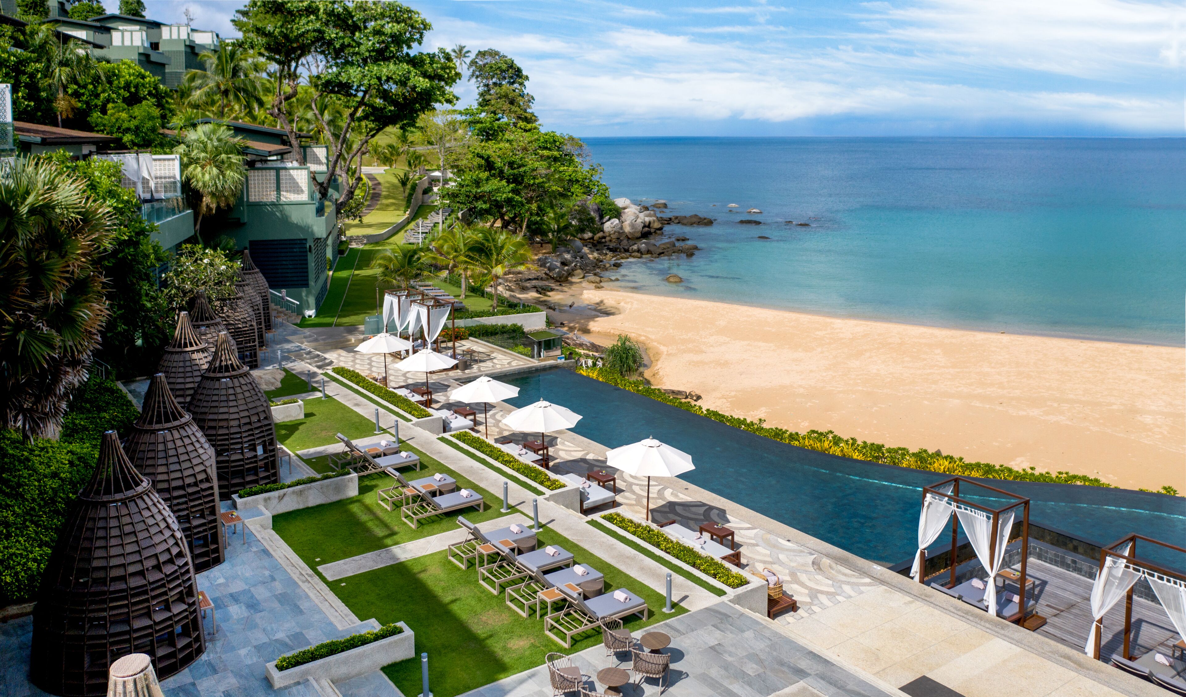 Un resort con zona de piscina, vista al mar y jardines tropicales.