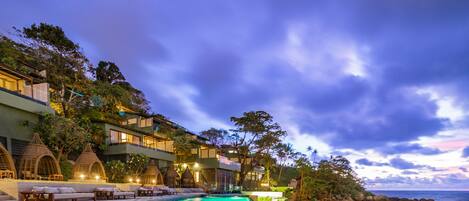 A resort with a swimming pool, beachfront, and multiple-story buildings with balconies.
