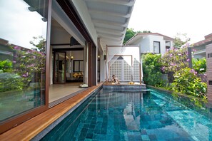 Un espace piscine moderne offrant une vue dégagée sur la piscine, avec une terrasse en bois et une véranda donnant accès à une pièce.