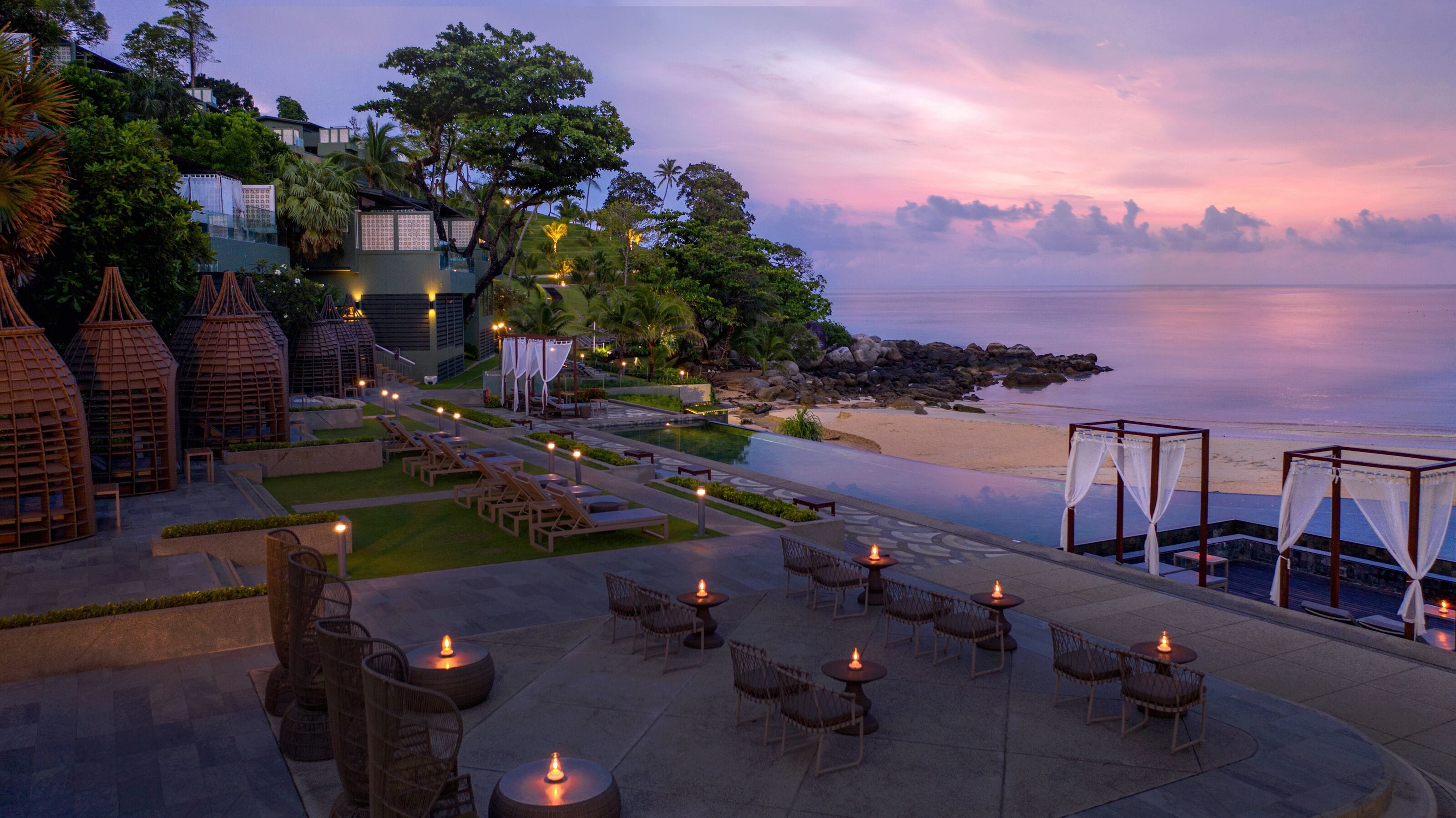 A resort with a pool, outdoor seating, and a beach view.