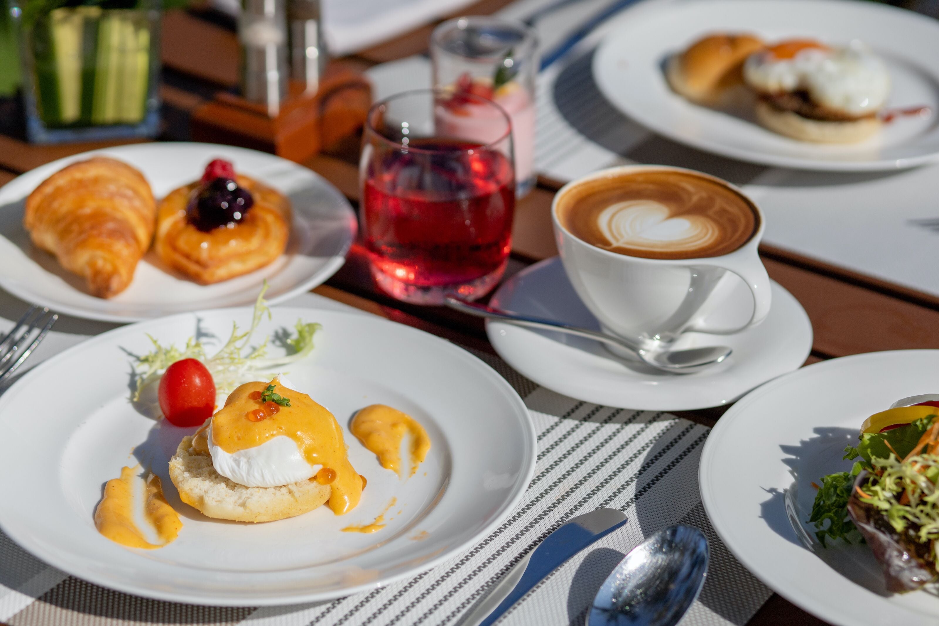 A table with various dishes including croissants, a poached egg, and a salad.