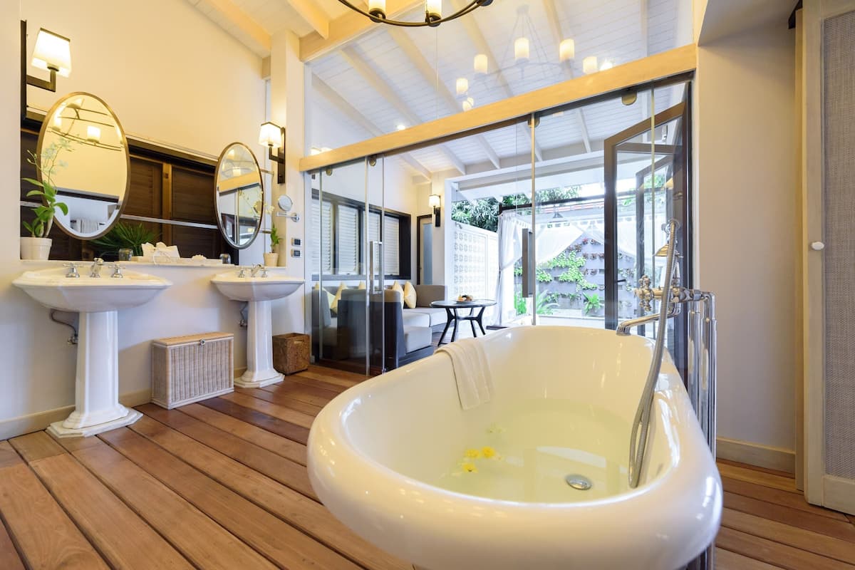 A bathroom with a freestanding bathtub, two pedestal sinks, and a large mirror.