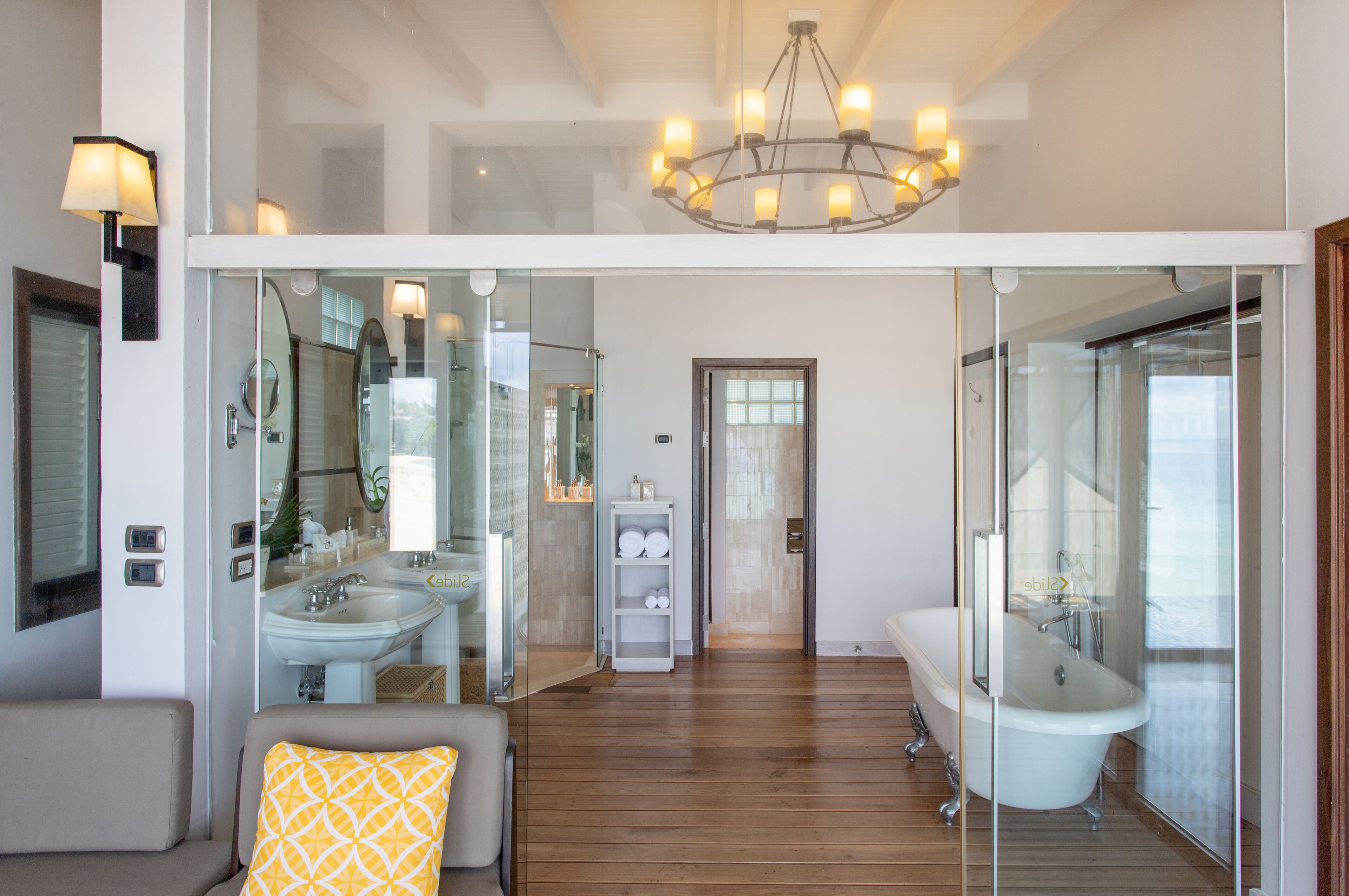 Un baño moderno con una bañera independiente, ducha con mampara de vidrio y tocador con lavamanos y espejo.