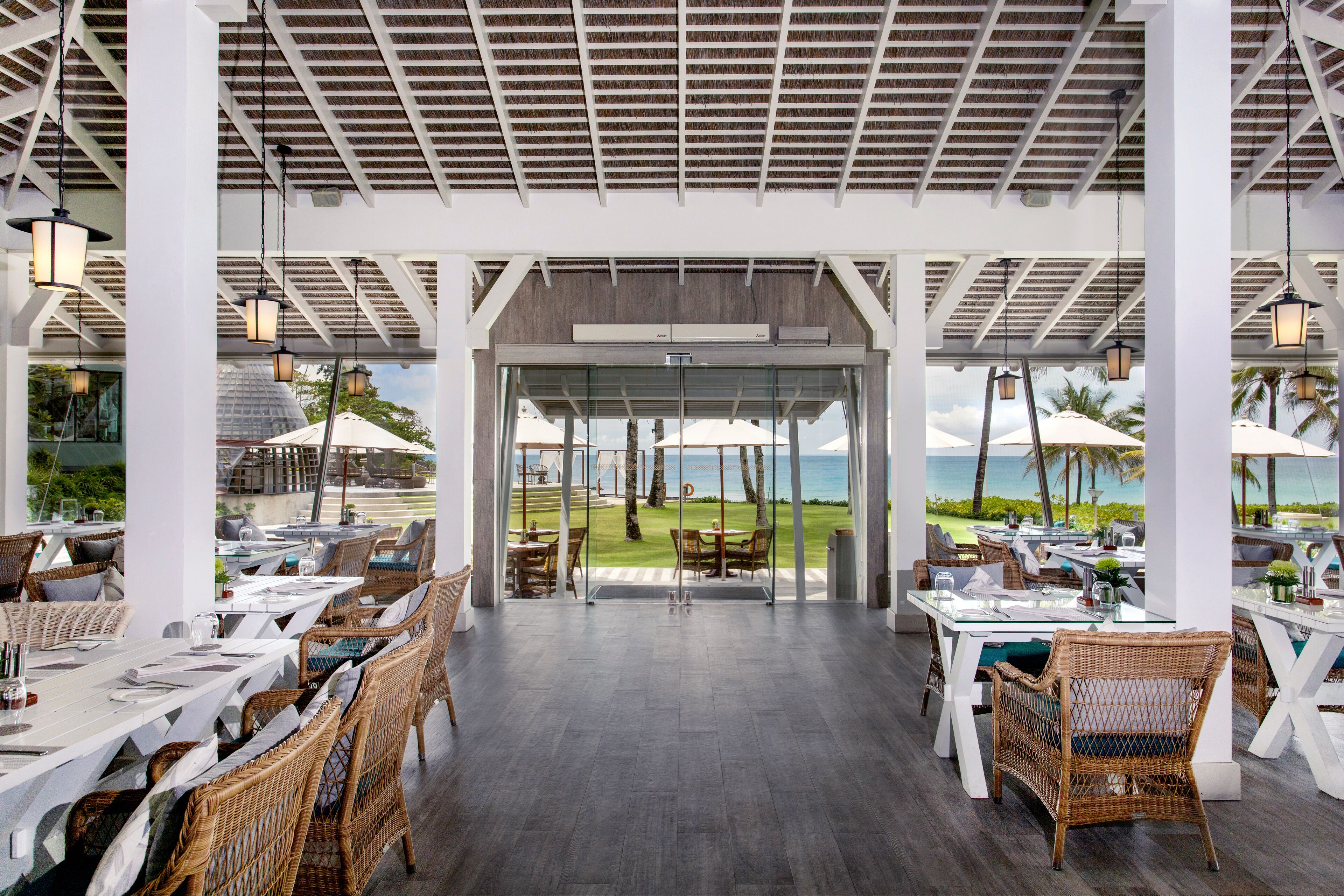 An outdoor dining area with wicker furniture and a view of the beach.