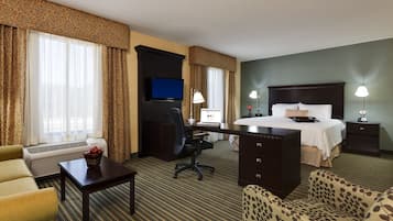 A hotel room with a bed, desk, computer, and two chairs.