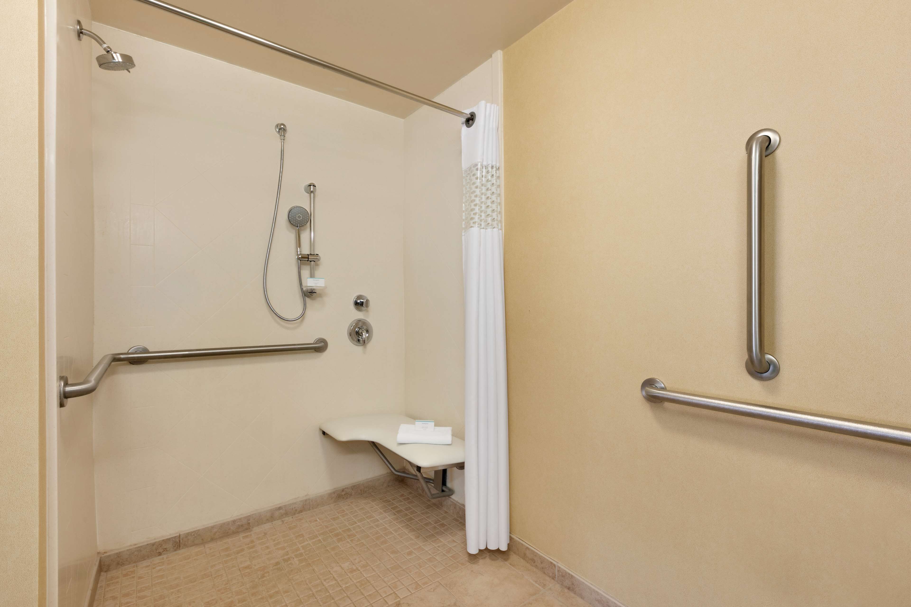 Baño accesible para personas con movilidad reducida, con barras de apoyo, ducha e inodoro.