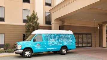 A blue van parked in front of a hotel with a sign that reads "IT'S A GOOD DAY FOR A GOOD DAY".