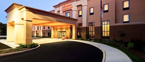 A hotel with a modern facade, a prominent entrance, and an American flag.