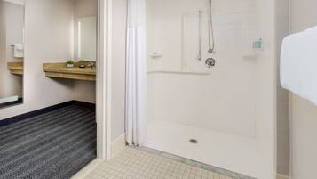 Ein modernes Badezimmer mit Dusche, Waschbecken mit Spiegel und Handtuchhalter.