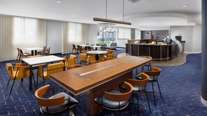 A modern hotel lobby with a central bar area, multiple seating arrangements, and a reception desk. - Courtyard by Marriott Keene Downtown (Keene)