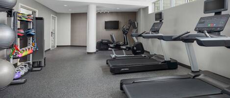 A gym with treadmills, exercise balls, and weights.