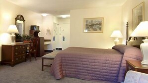 A hotel room with a bed, two bedside tables with lamps, a dresser, a chair, and a painting on the wall. - River Terrace Green River (Green River)