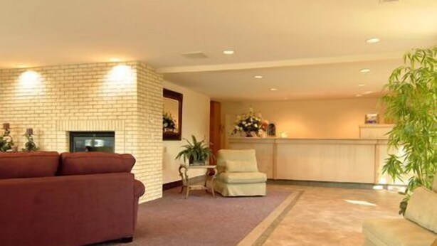 A living room with a red sofa, a small table with chairs, and a kitchen area in the background. - River Terrace Green River (Green River)