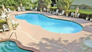 A swimming pool with a brick edge, surrounded by lounge chairs and a patio table. - River Terrace Green River (Green River)