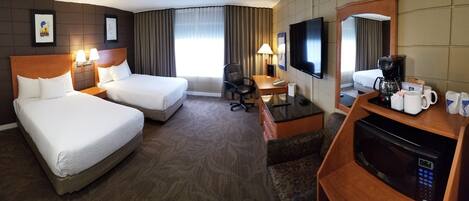 A hotel room with two beds, a desk with a chair, a television, a coffee maker, and a microwave.