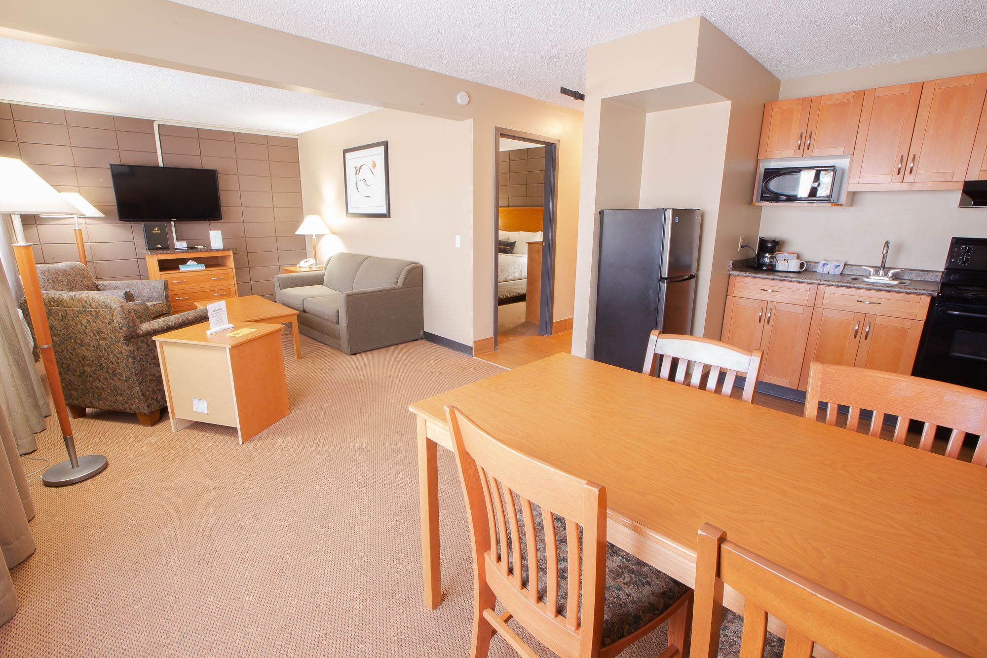 Habitación de hotel con sala de estar, kitchenette y un dormitorio independiente.