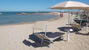 A beach with sun loungers and umbrellas, a sandy shore, and the sea in the background. - Residence Mediterraneo (Rimini)