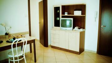 Ein Zimmer mit Esstisch, Stühlen, einem Fernseher auf einem Schrank und einer Tür.