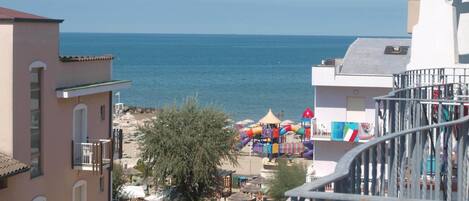 A coastal view with a beach, a playground, and buildings with balconies.