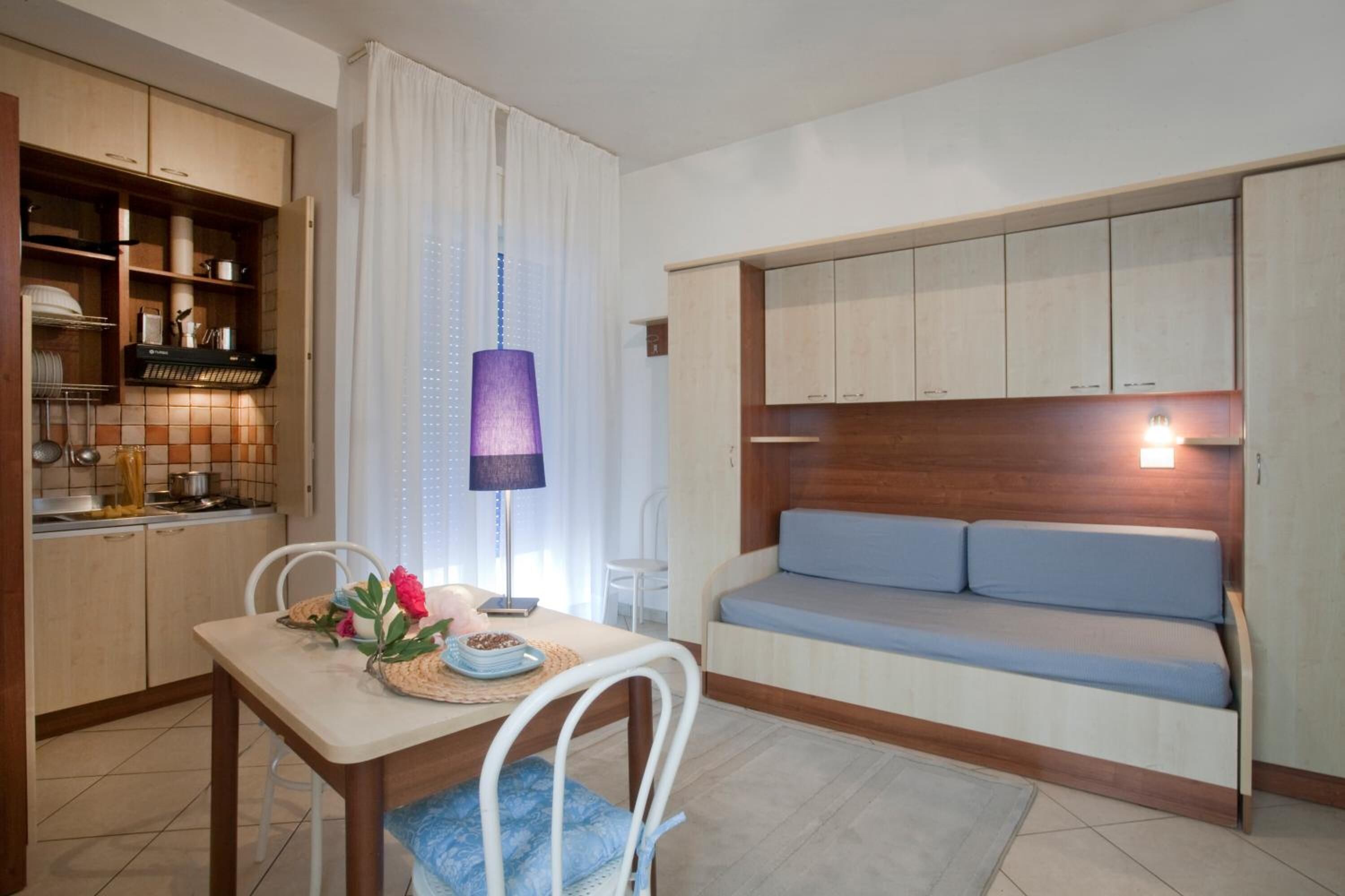 Cocina compacta con armarios de madera, una mesa de comedor con sillas y un banco empotrado con cojines.
