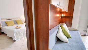 A hotel room with two beds, a wooden headboard, and a small kitchenette.