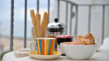 A table with a striped cup, a bowl of pastries, and a jar of jam.