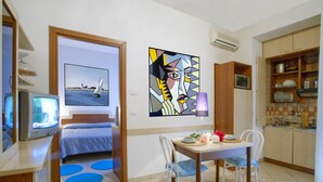 A compact living space with a bed, a dining area, a kitchen, and a TV. - Residence Mediterraneo (Rimini)