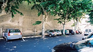 Un espace de stationnement avec plusieurs voitures, un mur de briques et des arbres.