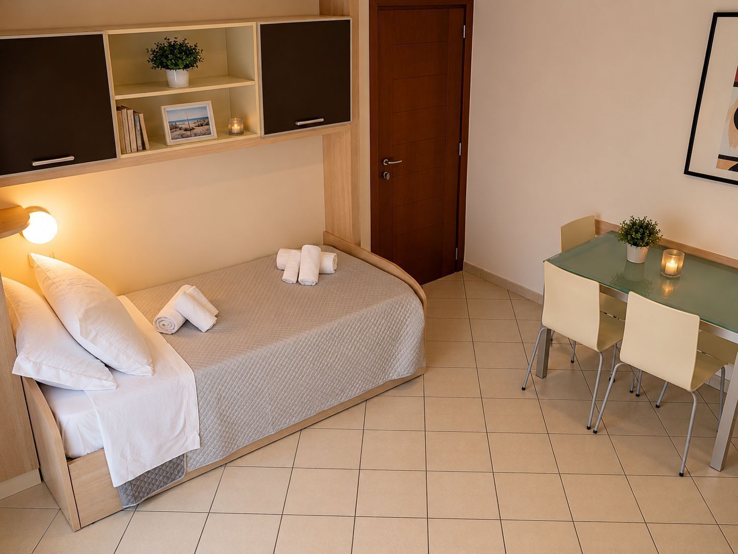 Un dormitorio con cama, mesitas de noche, escritorio y puerta.