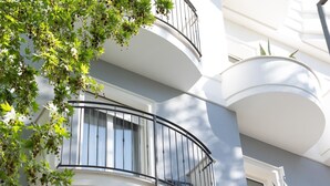 Un edificio de varios pisos con balcones, una ventana y una planta.