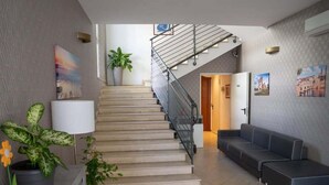 Un interior moderno con una escalera, un sofá y una planta en maceta.