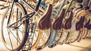 Una fila de bicicletas con asientos marrones, cada una sujeta a un portaequipajes metálico.