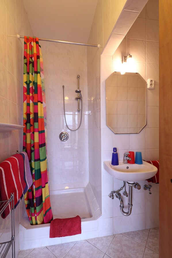 Un baño con ducha, lavamanos y espejo.