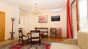 A living room with a sofa, chairs, a chandelier, a television, and a red curtain. - Budavar Bed and Breakfast (Budapest)