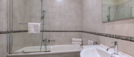 A modern bathroom with a glass-enclosed shower, a freestanding bathtub, a sink, and a toilet.