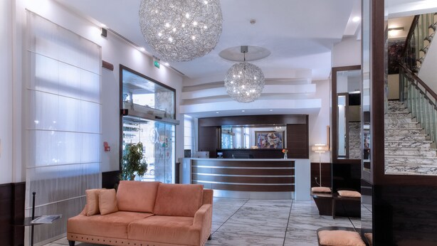 A lobby with a reception desk, a sofa, and a staircase. - B&B Hotels Park Hotel Mondovi (Mondovi)