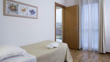 A hotel room with a bed, a window with curtains, and a view of buildings outside.