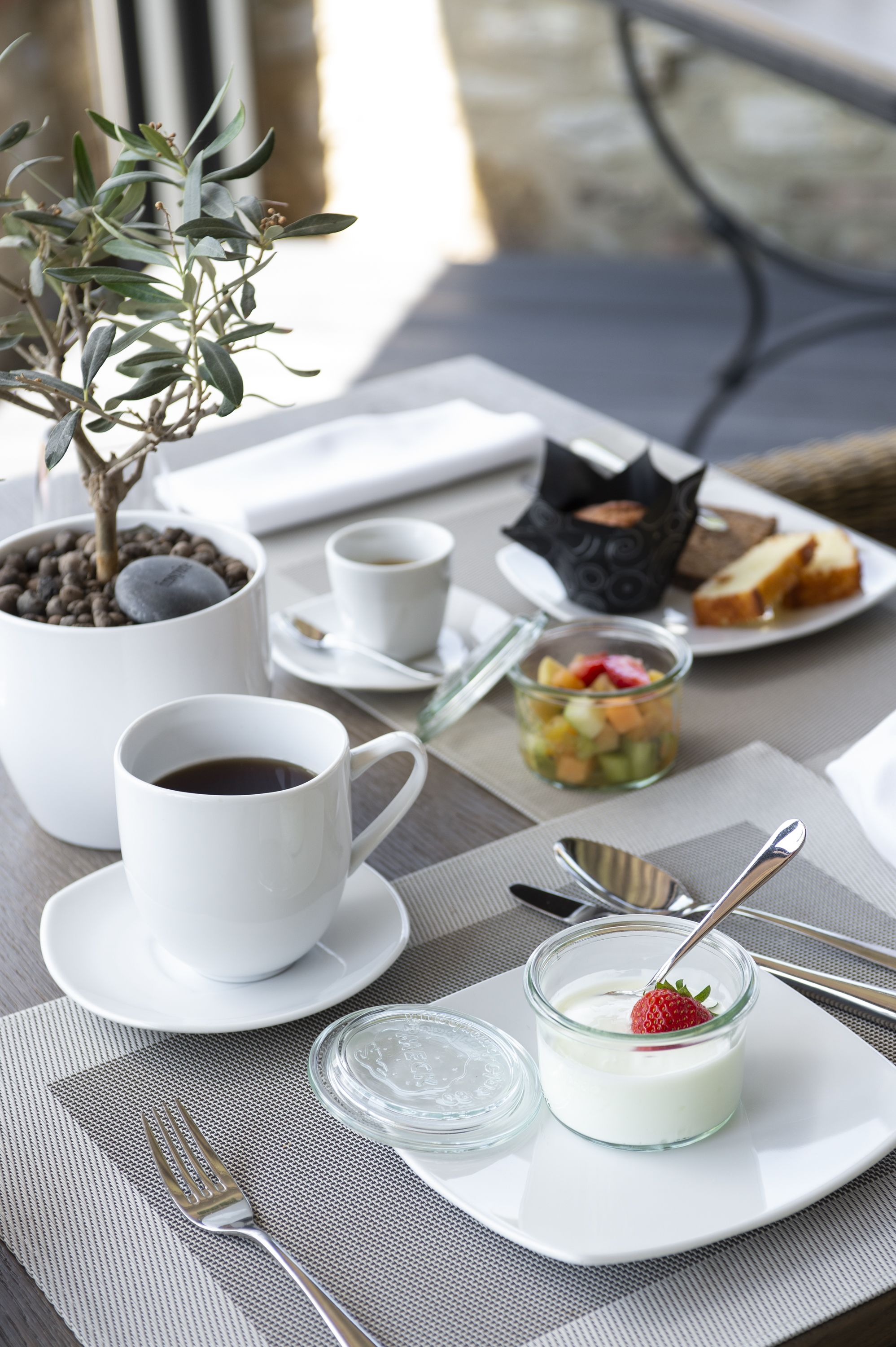 Een ontbijttafel met koffie, fruit en een dessert.
