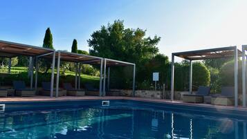 Alberca al aire libre, sombrillas en la alberca y camastros